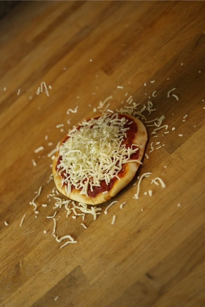 A small tomato pizza on the wooden counter